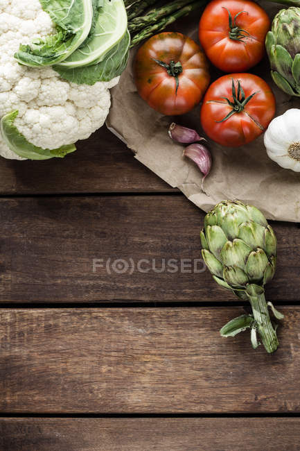 Couve-flor, alcachofras, espargos, alho e tomates sobre mesa de madeira — Fotografia de Stock