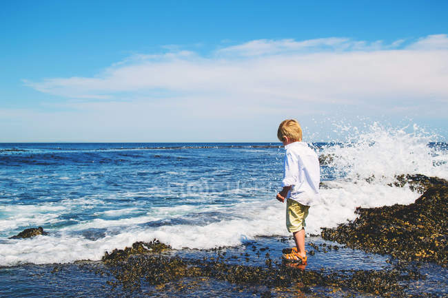 Boy standing on beach and looking at waves — Stock Photo