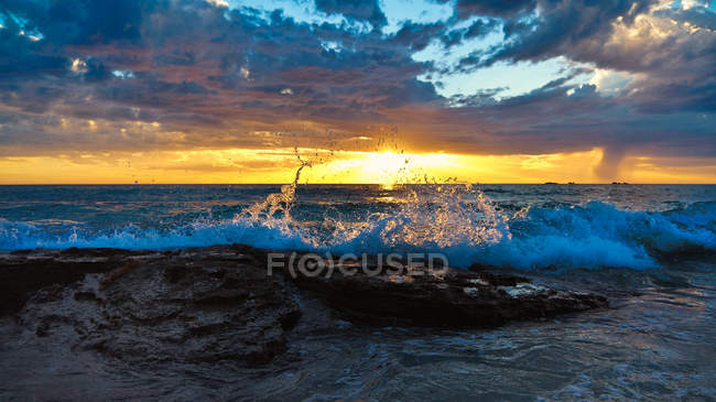 Vista panorâmica da costa ao pôr do sol sob nuvens — Fotografia de Stock