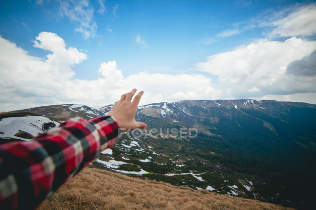 Живописный пейзаж с человеческой рукой на переднем плане — стоковое фото