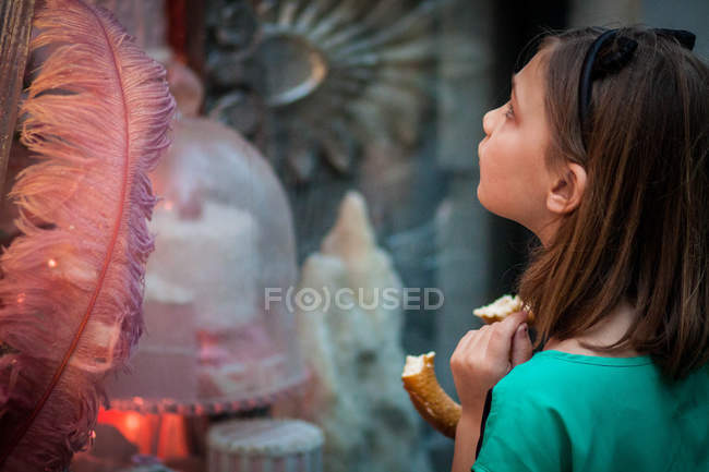 Beautiful little girl standing and looking at window shopping — Stock Photo