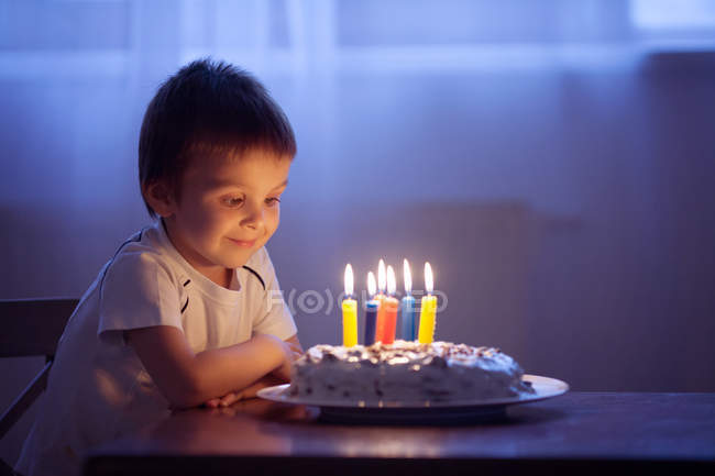 Маленький мальчик празднует день рождения с тортом и свечами — стоковое фото