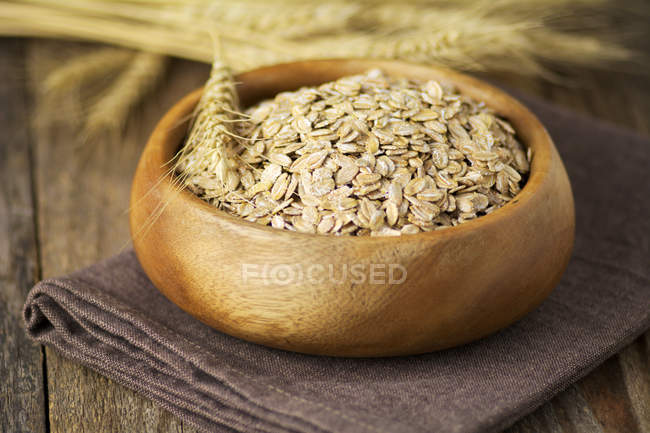 Organic rolled oats in wooden bowl — Stock Photo