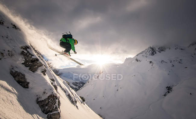 Austria, Free-ride skier jumping off rock in mountains — Stock Photo