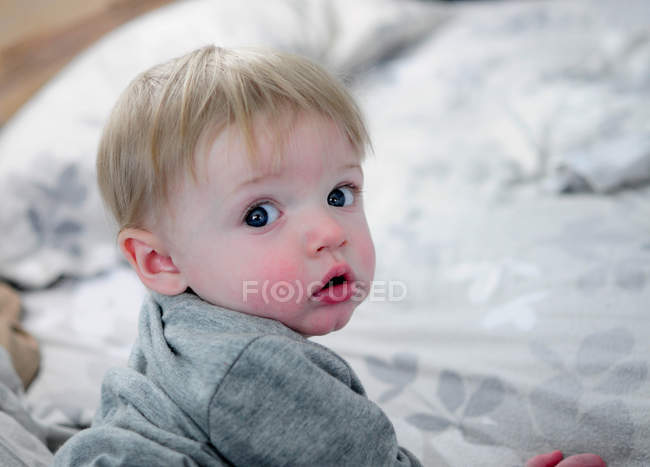 Loira bonito bebê menino rastejando na cama — Fotografia de Stock