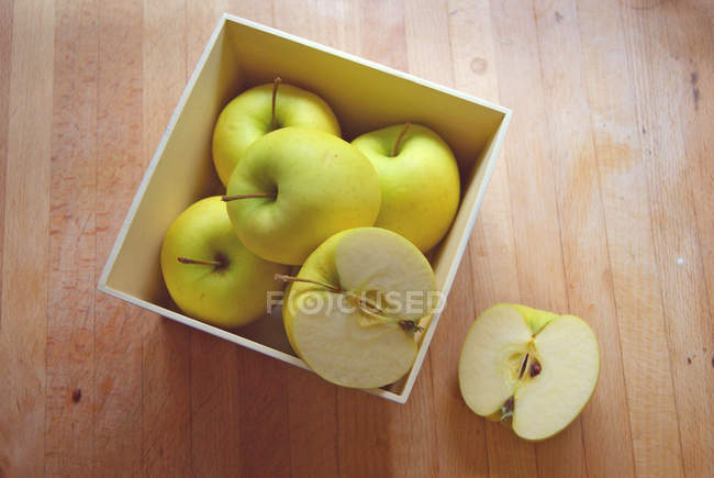 Fresh tasty apples in box over wooden background — Stock Photo