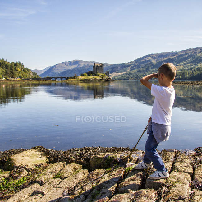Великобритания, Шотландия, Мальчик смотрит на замок Айлин Донан — стоковое фото
