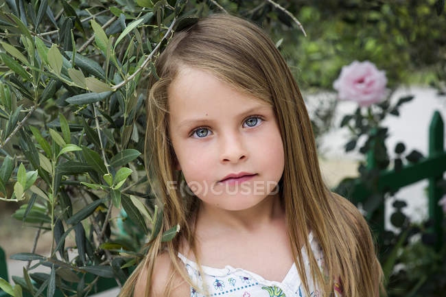 Portrait de petite fille aux cheveux longs devant les plantes — Photo de stock