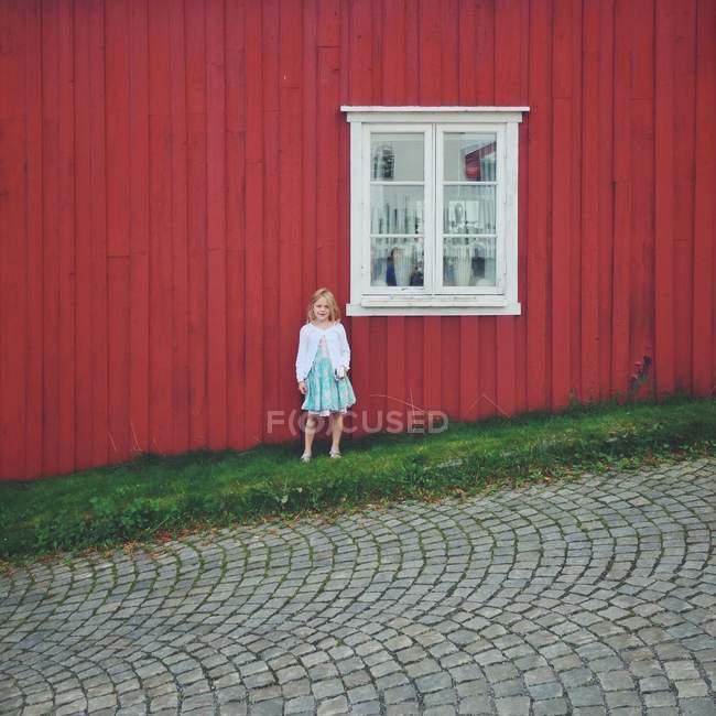 Menina de pé contra a casa vermelha — Fotografia de Stock