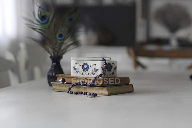 Zusammensetzung von Halskette, Schmuckschatulle und Büchern auf dem Tisch — Stockfoto