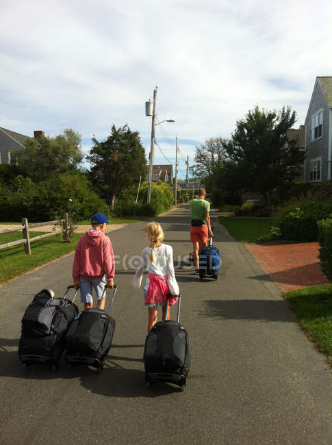 Батько з дітьми, що йдуть на вулицю з багажем — стокове фото