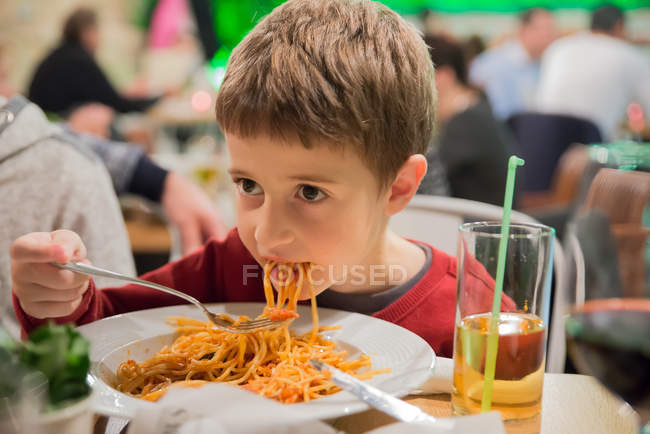 Маленький хлопчик їсть спагеті з тарілки — стокове фото
