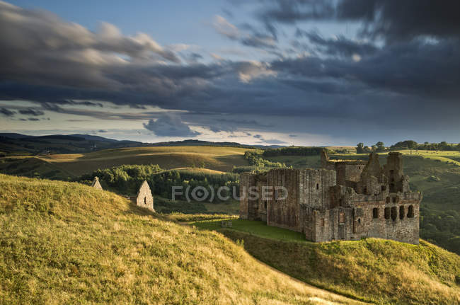 Руины замка Криктон и окружающий ландшафт видны с холма, покрытого засохшей травой, Патхед, Мидлотиан, Шотландия, Великобритания — стоковое фото