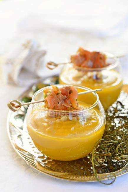 Creamy chickpea carrot soup with crispy walnut and smoked trout in glasses — Stock Photo