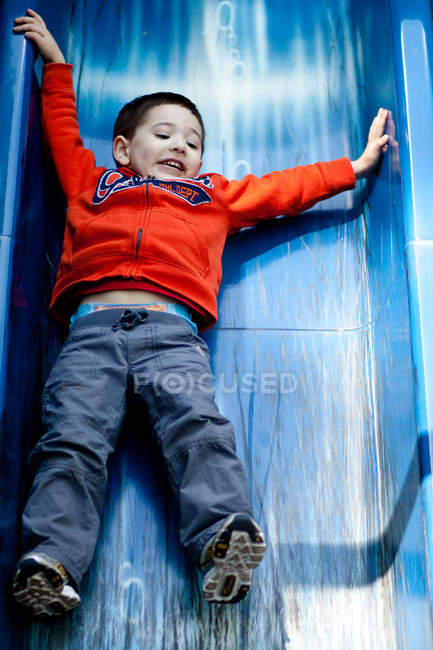 Милый маленький мальчик веселится на горке на детской площадке — стоковое фото