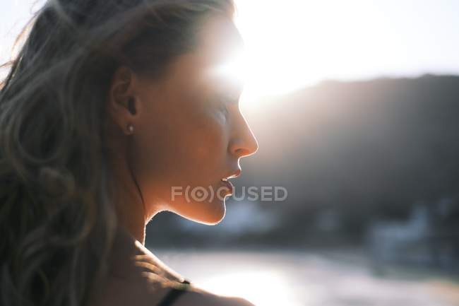 Primer plano de la mujer pensativa en la playa en retroiluminación - foto de stock