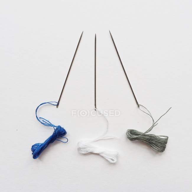 Three needles with thread against white background — Stock Photo