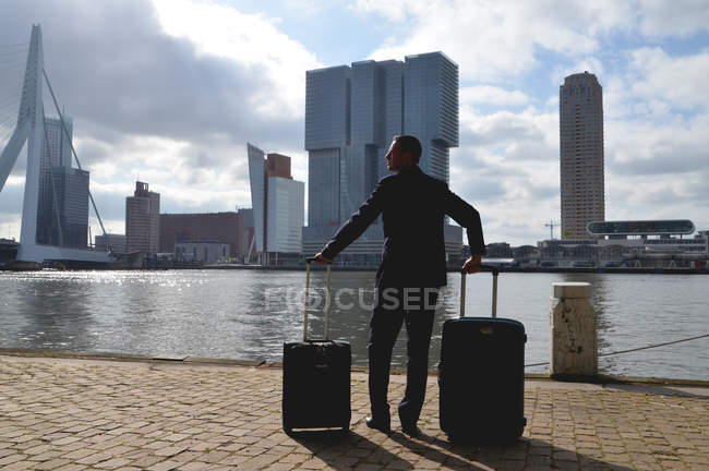 Нидерланды, Роттердам, бизнесмен с чемоданами на городской набережной — стоковое фото