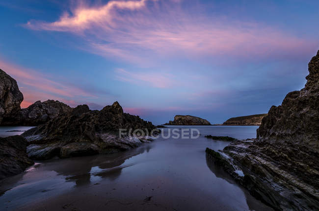 Rochers au bord de la mer en eau calme au crépuscule — Photo de stock