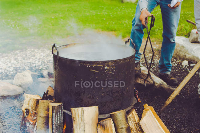 Imagen recortada del hombre cocinando pescado hervir en el parque - foto de stock