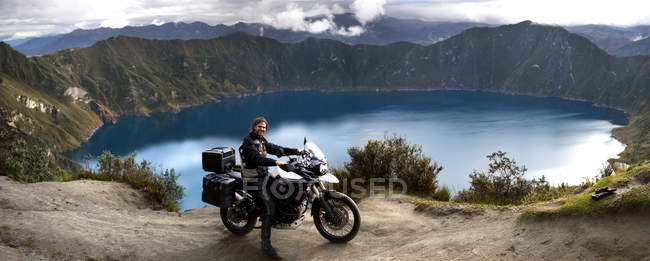 Еквадор, людина на мотоциклі стоячи проти озеро в Лагуна Кілотоа — стокове фото