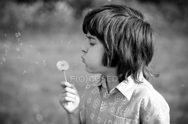 Мальчик с закрытыми глазами дул одуванчиком в поле — стоковое фото