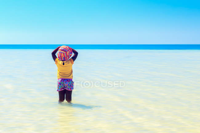 Вид сзади на девочку, стоящую в море — стоковое фото