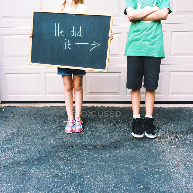 Abgeschnittenes Bild von zwei Kindern mit Warntafel — Stockfoto