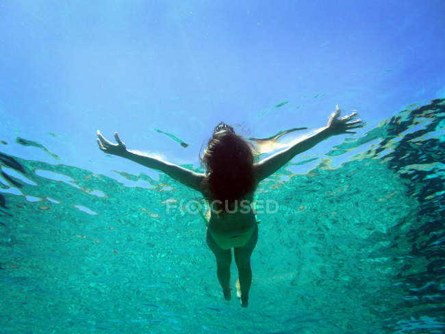 Подводный вид на женщину, плывущую по воде — стоковое фото