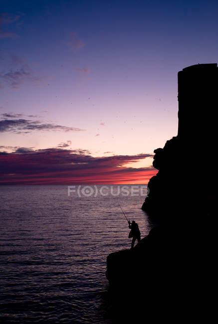 Croácia, Dubrovnik-Neretva, Dubrovnik, Silhueta do homem que pesca da formação de rocha — Fotografia de Stock