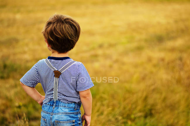 Menino com a mão no quadril em pé no campo — Fotografia de Stock