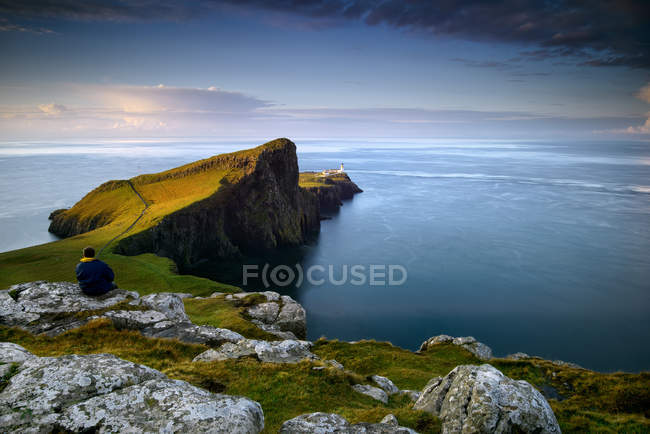 Mann sitzt auf einem Felsen und blickt auf das Meer, Neist Point, Schottland — Stockfoto