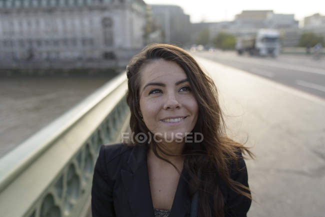 Retrato de una mujer sonriente caminando sobre un puente en la ciudad — Stock Photo
