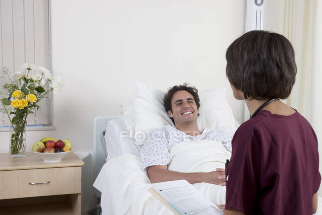 Счастливый молодой человек в офисе медицинской клиники с женщиной-врачом — стоковое фото