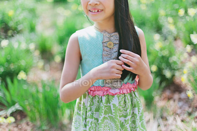 Mädchen mit sommergemustertem Kleid spielt mit Haaren im Feld — Stockfoto