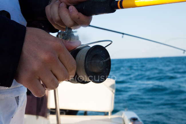 Imagem cortada do homem segurando haste de pesca no barco — Fotografia de Stock