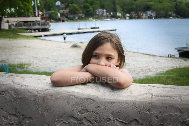 Pensativo menina inclinada na parede na praia — Fotografia de Stock