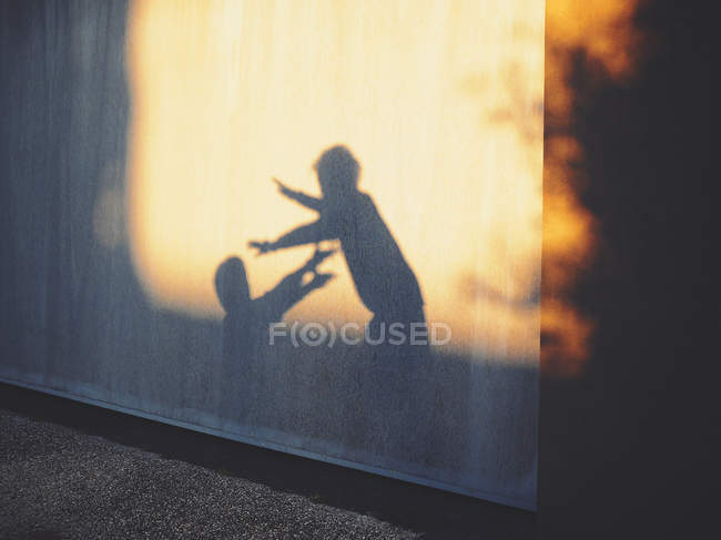 Sombras de duas crianças brincando contra a parede — Fotografia de Stock