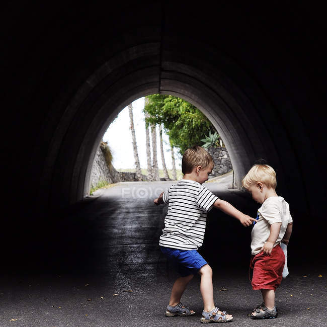 Deux petits frères caucasiens s'amusent sous l'arche en vacances — Photo de stock