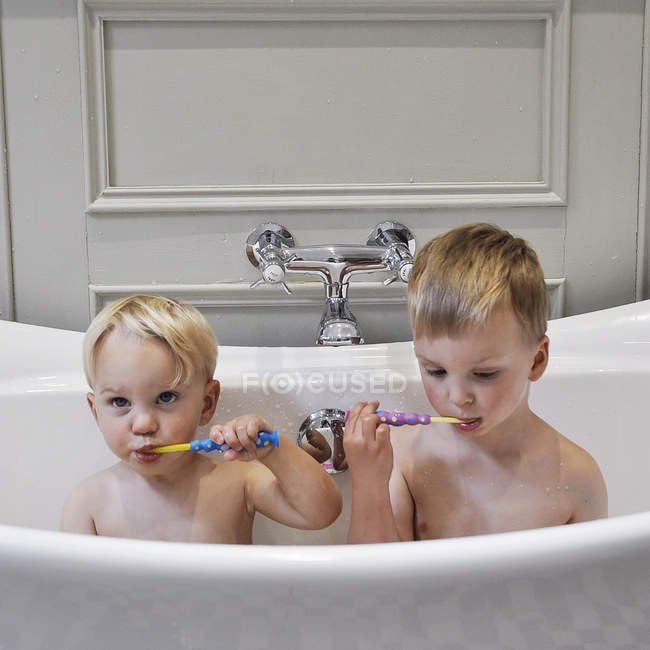 Два милих маленьких брати у ванній прибирають зуби разом — стокове фото