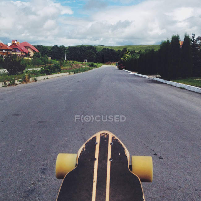 Closeup view of skateboard on empty rural road — Stock Photo