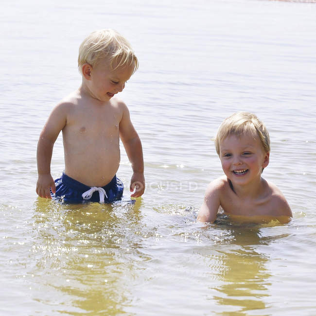 Deux jeunes frères caucasiens s'amusent dans l'eau — Photo de stock