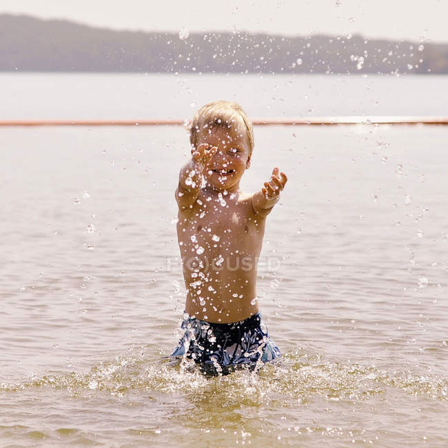 Sorridente ragazzo spruzzi d'acqua in mare — Foto stock
