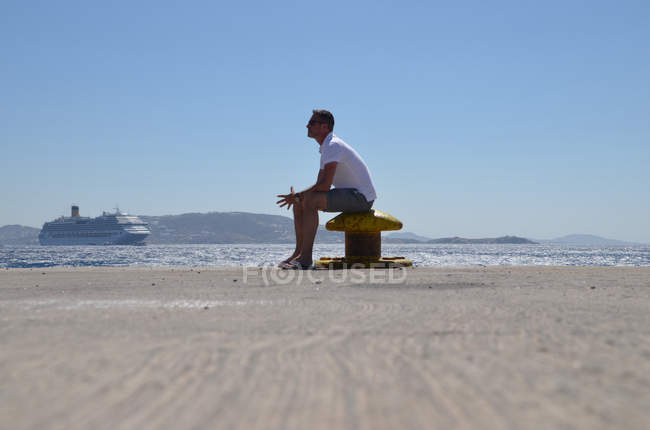 Mann sitzt am Strand und wartet auf Schiff — Stockfoto