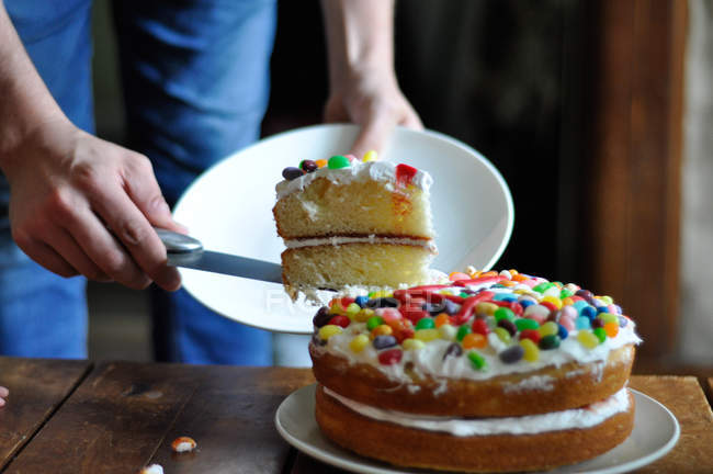 Обрезанное изображение человека, подающего торт на стол — стоковое фото