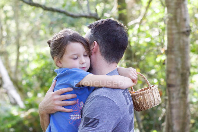 Padre abrazándose con su hija pequeña en el parque - foto de stock