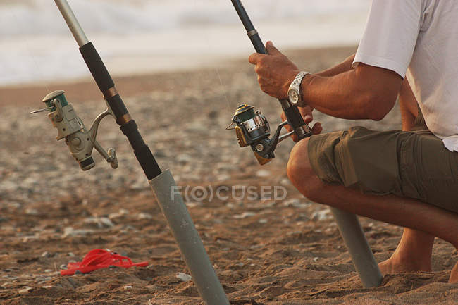 Abgeschnittenes Bild eines Mannes, der am Sandstrand fischt — Stockfoto