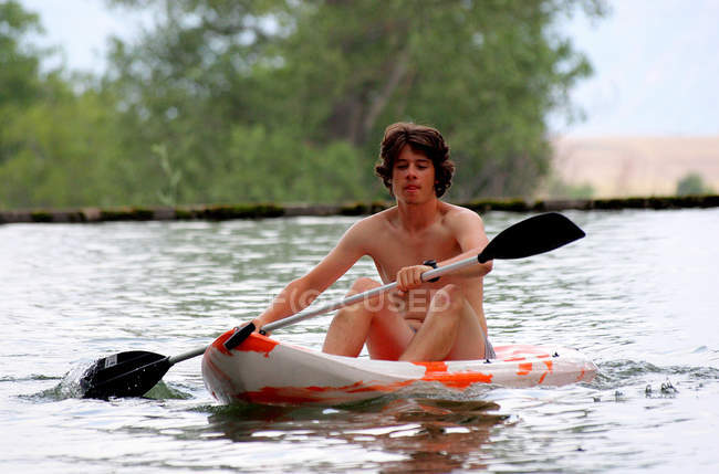 Centrado chico adolescente piragüismo en el agua - foto de stock