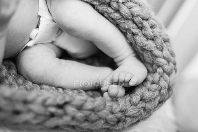 Imagen recortada de las piernas desnudas del recién nacido con pañal, monocromo - foto de stock