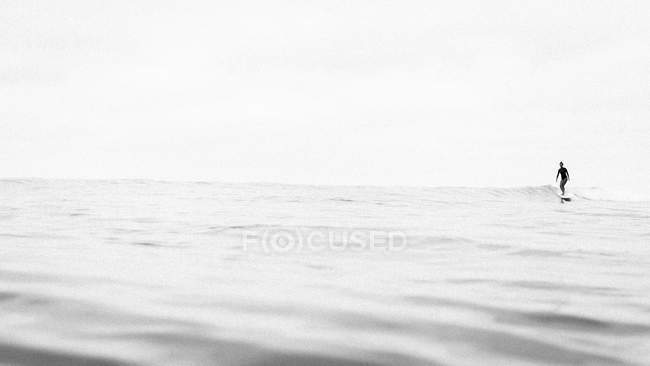 Silhouette of woman surfing on waves in ocean — Stock Photo